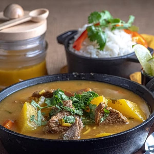 Hearty Latin-American beef stew with vegetables and cilantro, served with white rice and lime.