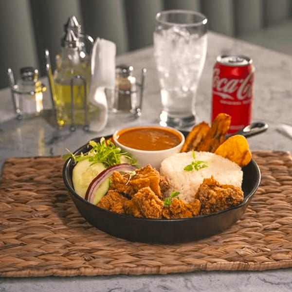 Mamajuana Restaurant's fried chicken with rice, plantains, salad, and sauce, with a Coca-Cola.
